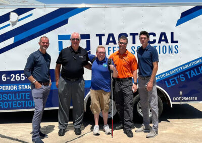 photo of founder Andrew Crane standing in front of Guiding Paws' Into the Light trailer with with reps from sponsor Tactical Solutions