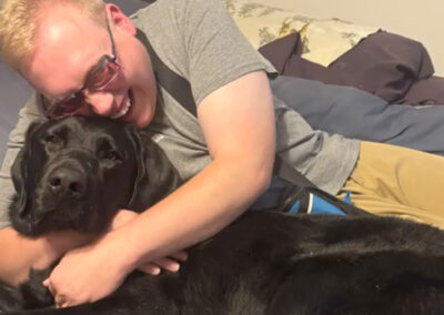 photo of Andrew hugging his black lab guide dog Jiminy